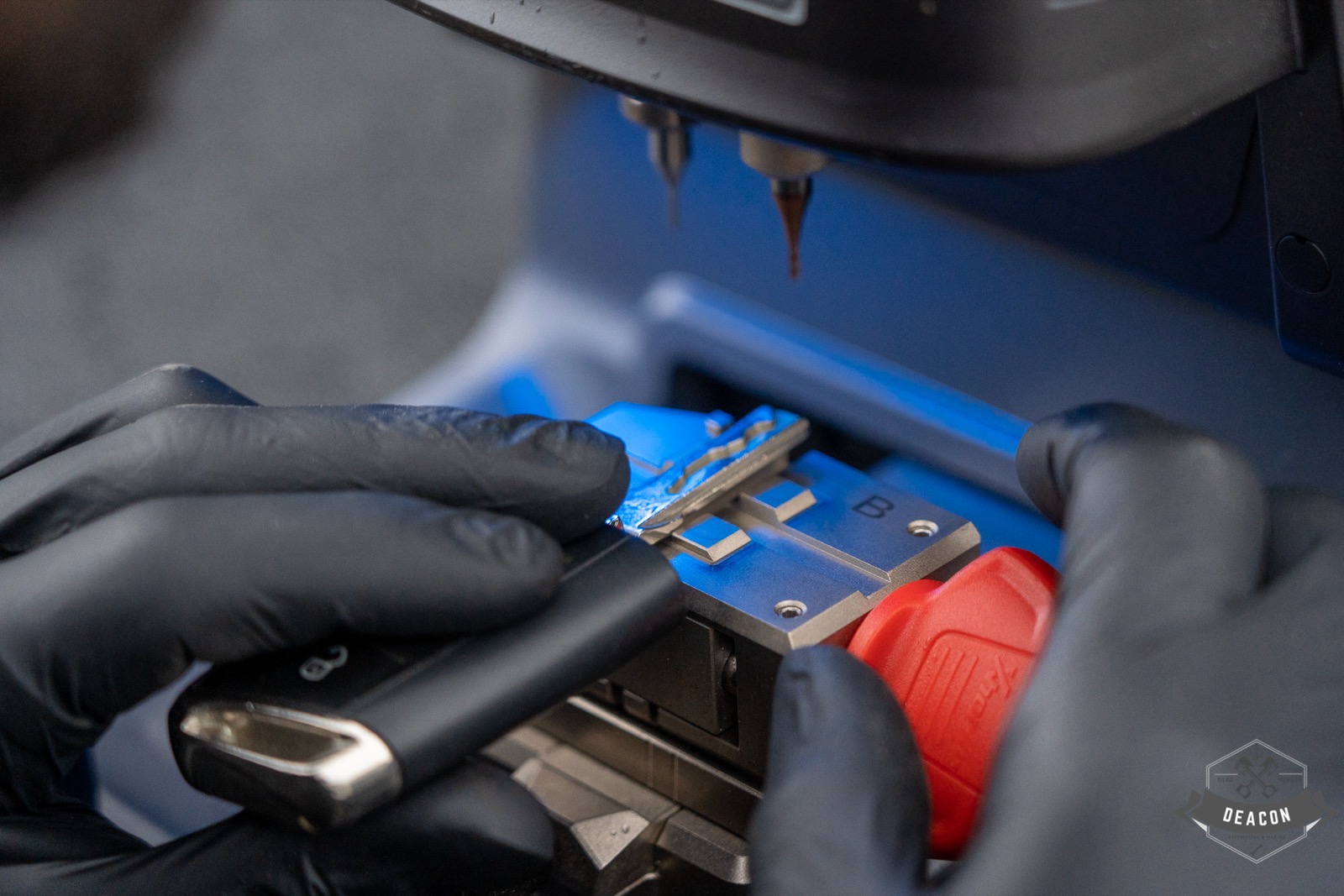 Gloved hands positioning a car key in Deacon’s key-cutting machine