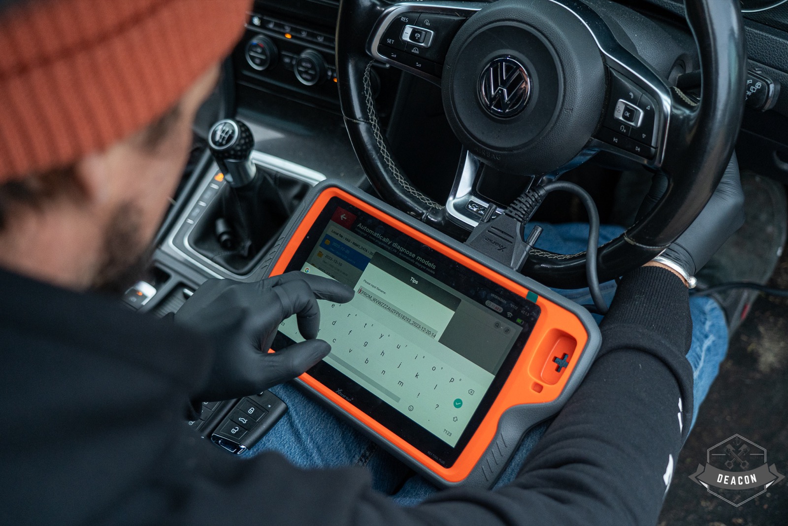 Deacon technician using a key-programming tablet inside a Volkswagen